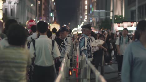 Policías-Japoneses-Con-Chalecos-Parpadeantes-Observando-A-La-Multitud-Durante-El-Festival-Gion-Matsuri-En-Kyoto,-Japón---Plano-Medio