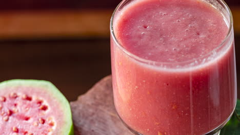 Glass-of-red-guava-juice-and-sliced-guava-slice-on-wooden-background
