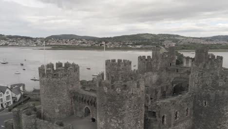 Medieval-landmark-historic-Conwy-castle-aerial-view-rising-tilt-down-above-Welsh-seaside-town