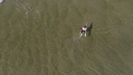 Surfer-walking-through-the-water-aerial-shot