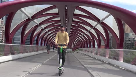 Zoom-out-as-two-men-ride-scooters-on-the-urban-Peace-Bridge-in-Calgary