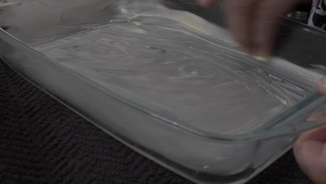 Adult-Female-Greasing-Inside-Of-Pyrex-Dish-With-Butter