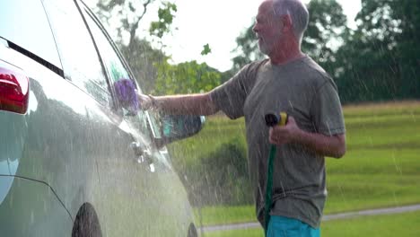 Slow-motion-of-man-washing-his-car-and-dancing-with-the-hose-and-soapy-rag