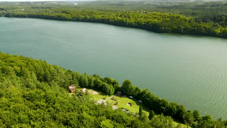 Brodno-Wielkie-Lake-in-Summer-season-with-Green-Forests-on-banks---Arial-turn-around-view