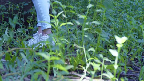 Close-up-view-of-a-young-girl-feet-and-sneakers-in-a-tropical-park-with-bushes-in-the-foreground
