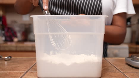 Mixing-the-dry-ingredients-for-a-dough-or-batter-in-a-plastic-measuring-container-with-a-whisk---side-view