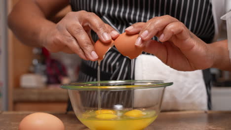 Cracking-organic-free-range-eggs-into-a-glass-bowl-to-mix-and-add-to-a-homemade-recipe---side-view-in-slow-motion