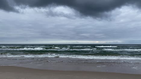 Dark-storm-clouds-over-the-sea-and-sandy-beach---wide-shot