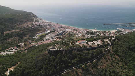 Top-down-view-Sesimbra-Natural-coastline-and-Castle-on-hilltop,-mesmerizing-Landscape---Portugal