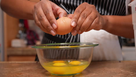Cracking-eggs-into-a-glass-bowl-for-mixing-or-adding-to-a-homemade-recipe---side-view-isolated