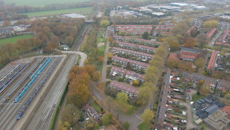 Aerial-of-training-driving-past-small-town-in-autumn