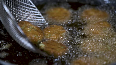 Deep-Frying-Tod-Man-Pla-Thai-Fish-Cakes-in-Hot-Oil-with-Skimmer---Close-Up