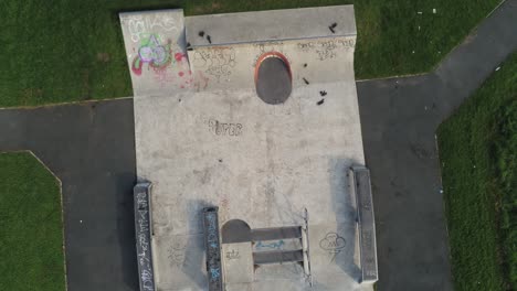 Grungy-public-park-graffiti-covered-shaped-concrete-play-area-aerial-view-rising