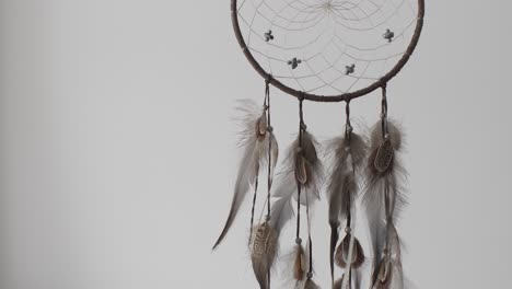 Hanging-Dreamcatcher-Indoors-Gently-Swaying-Against-Plain-Background