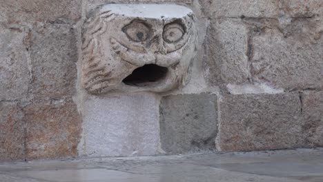 In-old-town-Dubrovnik,-Croatia,-a-cat-climbs-into-a-statue's-mouth