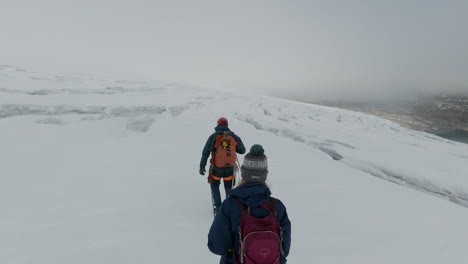 Dos-Excursionistas-Viajan-A-Través-De-Un-Vasto-Glaciar-Nevado-En-Un-Día-Nublado-En-Jostedal,-Noruega
