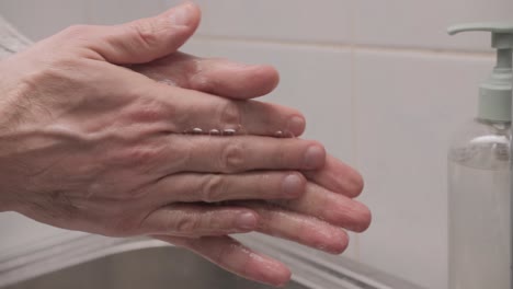 Man-washing-her-hands-with-liquid-soap-in-the-bathroom