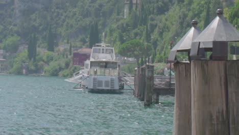 Pubilc-transportation-ferry-on-the-lake-garda-in-Riva-Del-Garda-North-Italy-in-slowmotion,-close-up-shot-with-mountains-in-the-background