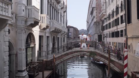 Couple-stands-on-bridge-above-venice-canal