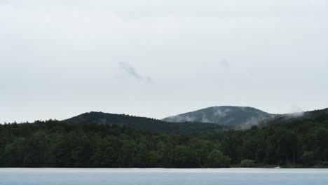 Cloudy-green-mountain-range-with-cloud-cover-over-looking-foggy-lake