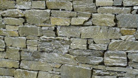 Slow-motion-close-up-water-trickling-down-stone-brick-wall