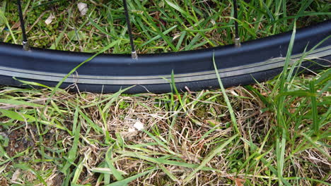 A-close-up-shot-of-a-thin-road-bike-tyre-being-pumped-up-on-a-grassy-surface