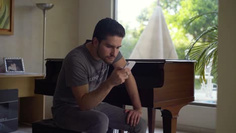 Young-man-checking-phone-right-infront-of-his-piano