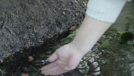 Dipping-hand-in-natural-clear-water-stream