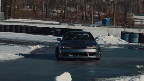 Tracking-shot-of-a-fast-Nissan-Silvia-drifting-on-a-wet-track-during-a-sunny-winter-day
