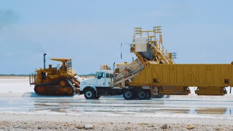 Trucks-Driving-Over-The-Salt-Flat-In-Kralendijk,-Bonaire-For-Salt-Loading---medium-shot