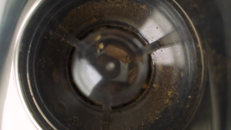 Up-close-overhead-view-of-fresh,-brown-coffee-beans-being-ground-in-fancy-electric-grinder-for-morning-coffee-in-slow-motion