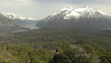 Aerial-shot-of-an-unrecognizable-man-reaching-a-viewpoint-of-Patagonian-lakes-and-mountains