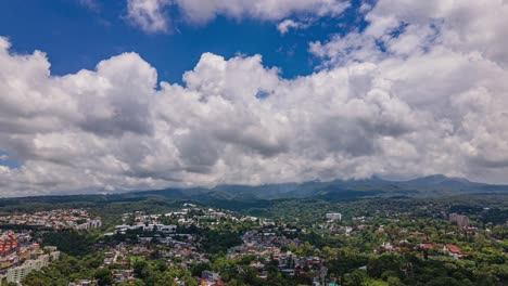 Aerial-drone-lapse-view-of-clouds-rolling-above-Cuernavaca-city,-on-a-partly-sunny-day,-in-Morelos,-Mexico,-America---Tracking,-hyperlapse-shot
