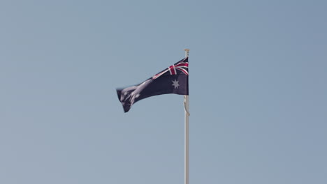 An-Australian-national-flag-on-a-flag-pole-flaps-in-the-wind-on-a-little-breeze-day-in-Australia
