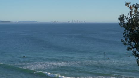 Surfers-Riding-Big-Blue-Waves-During-Summer---Greenmount-Beach-In-Coolangatta---Surfers-Paradise-In-The-Distance---Gold-Coast,-Australia