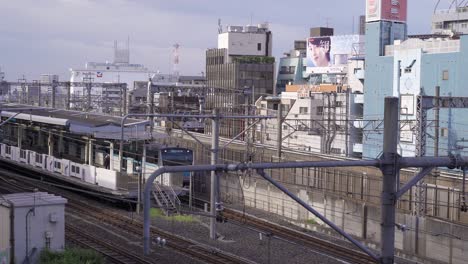 Tren-De-Cercanías-Japonés-Conduciendo-A-La-Estación-Con-El-Telón-De-Fondo-Del-Típico-Paisaje-Urbano-Japonés