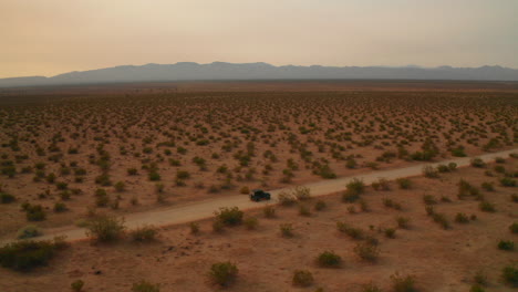 A-four-wheel-drive-jeep-on-a-dirt-road-at-sunset-in-the-Mojave-Desert---aerial-view