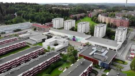 Aerial-view-towards-apartment-buildings-and-forest,-cloudy-day-in-Bergsjon,-Gothenburg,-Sweden---dolly-drone-shot