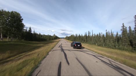 Black-suv-drives-down-a-country-road-during-daytime-captured-using-a-drone-close-up