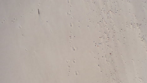 AERIAL:-Top-View-of-Sandy-Beach-with-Footprints-in-the-Sand