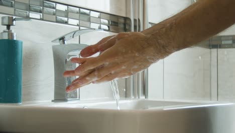 Mann,-Der-Seife-Von-Händen-Und-Armen-Abspült,-Hautnah-In-Einem-Waschbecken-Im-Badezimmer-In-Superlangsamer-Bewegung