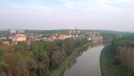 Sugar-factory-in-Melnik-along-Elbe-River-in-autumn-morning,-aerial-pan