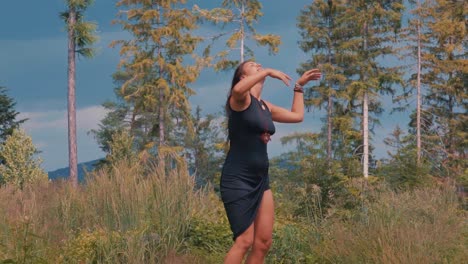 Slow-motion-shot-of-carefree-young-caucasian-girl-wearing-short-blue-navy-dress-with-arms-up-dances-in-forest-at-dusk,-handheld