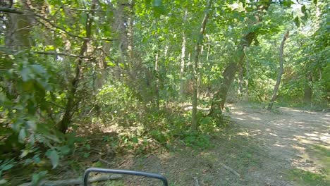 Point-of-view-while-driving-an-off-road-vehicle-on-a-curvy-trail-thru-the-woods-on-a-summer-adventure