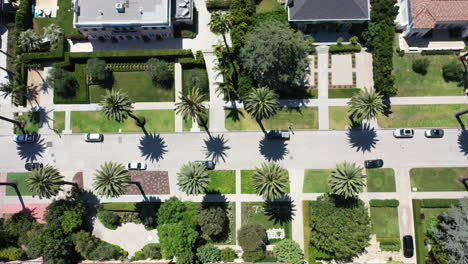 Drone-pans-over-palm-tree-and-McMansion-lined-street-in-West-Hollywood,-Los-Angeles-California