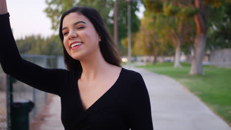 Beautiful-young-independent-hispanic-woman-looking-happy-as-she-waves-to-greet-a-friend-she-it-meeting-in-the-park