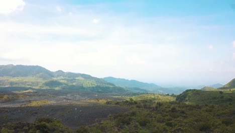 Drone-Aéreo-Volando-Sobre-Un-Hombre-Girando-Un-Bastón,-De-Pie-Sobre-Una-Roca-Con-Un-Hermoso-Paisaje-Volcánico-Cerca-Del-Volcán-Pacaya,-Guatemala