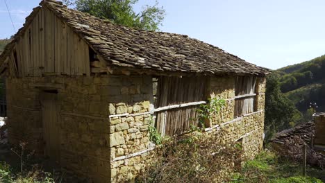 Cabaña-Con-Paredes-De-Piedra-Y-Techo-Gris-En-El-Paisaje-Rural-En-El-Pueblo-De-Montaña-En-Los-Balcanes