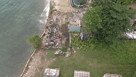 aerial-birds-eye-view-dolly-shot-of-a-abandoned-derelict-destroyed-bungalow-beach-resort-on-the-ocean-in-Thailand,-from-the-effects-of-covid-19-on-tourism