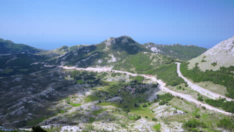Vista-Del-Vasto-Paisaje-Montañoso-Con-Valle-Verde,-Caminos-Y-Rocas-Del-Mausoleo-De-Njegos-En-La-Cima-Del-Monte-Lovcen-En-Montenegro,-Balcánico,-Cielo-Azul-Sobre-Montañas-Altas,-Toma-Escénica-Estática-De-4k